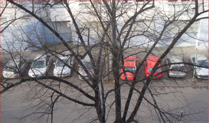 In einer Straße in Berlin parken Autos nach Farben sortiert.