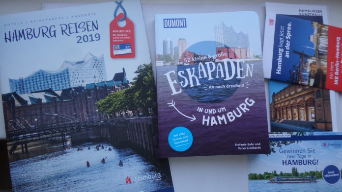 Hamburg-Reise-Broschüren, in der Mitte das Buch 52 kleine und große Eskapaden in und um Hamburg, Ab nach draußen