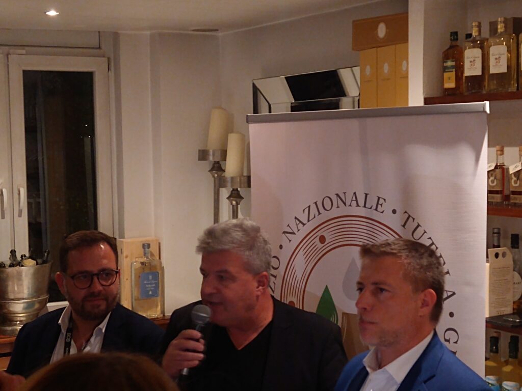 Conrad Rausch von Rausch Communications & PR (am Mikrophon). Rechts steht der Präsident des Consorzio Nazionale Grappa (CNG), Sebastiano Caffo. Im Restaurant "La Maremma" während der BCB. © 2024 Andreas Hagemoser, Aufnahmeort Berlin, -datum 14.10.'24