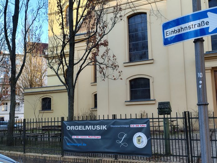 Plakat am Zaun der Luisenkirche auf dem Gierkeplatz in Berlin -Charlottenburg: Orgelmusik an der neuen Reil-Orgel immer donnerstags um 12:30 Uhr, Eintritt frei