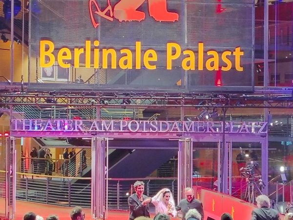Der Regisseur, Ilker Catak (Ilker Çatak), Hauptdarstellerin Özgü Namal, und Hauptdarsteller Herr Tansu Biçer (in GELBE BRIEFE in der Rolle des "Aziz") auf dem Roten Teppich vor dem Berlinale-Palast (Theater am Potsdamer Platz) nach der Vergabe des Hauptpreises der Internationalen Filmfestspiele Berlin, Frau Özgü Namal hält den Goldenen Bären gut sichtbar vor ihrem weißen Kleid.
